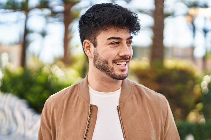 A man in a brown jacket smiling off to the side.